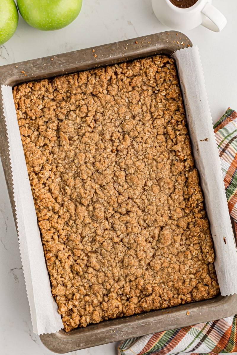 overhead view of freshly baked Caramel Apple Cheesecake Bars in a parchment- lined baking pan