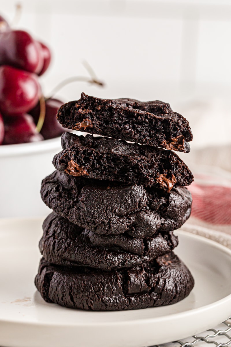 Stack of double dark chocolate cherry cookies on a white plate.