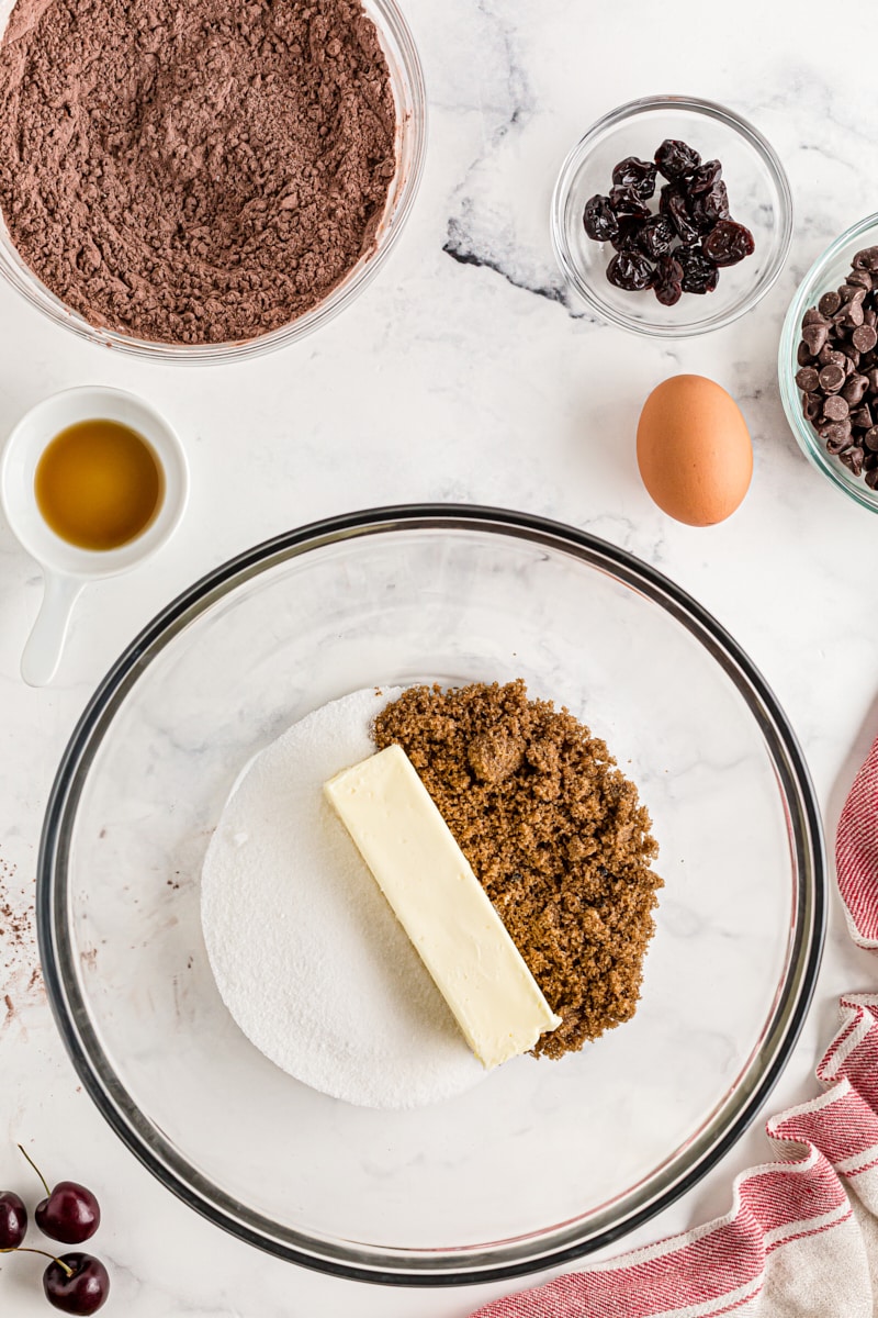 Overhead view of butter, brown sugar, and sugar in glass mixing bowl