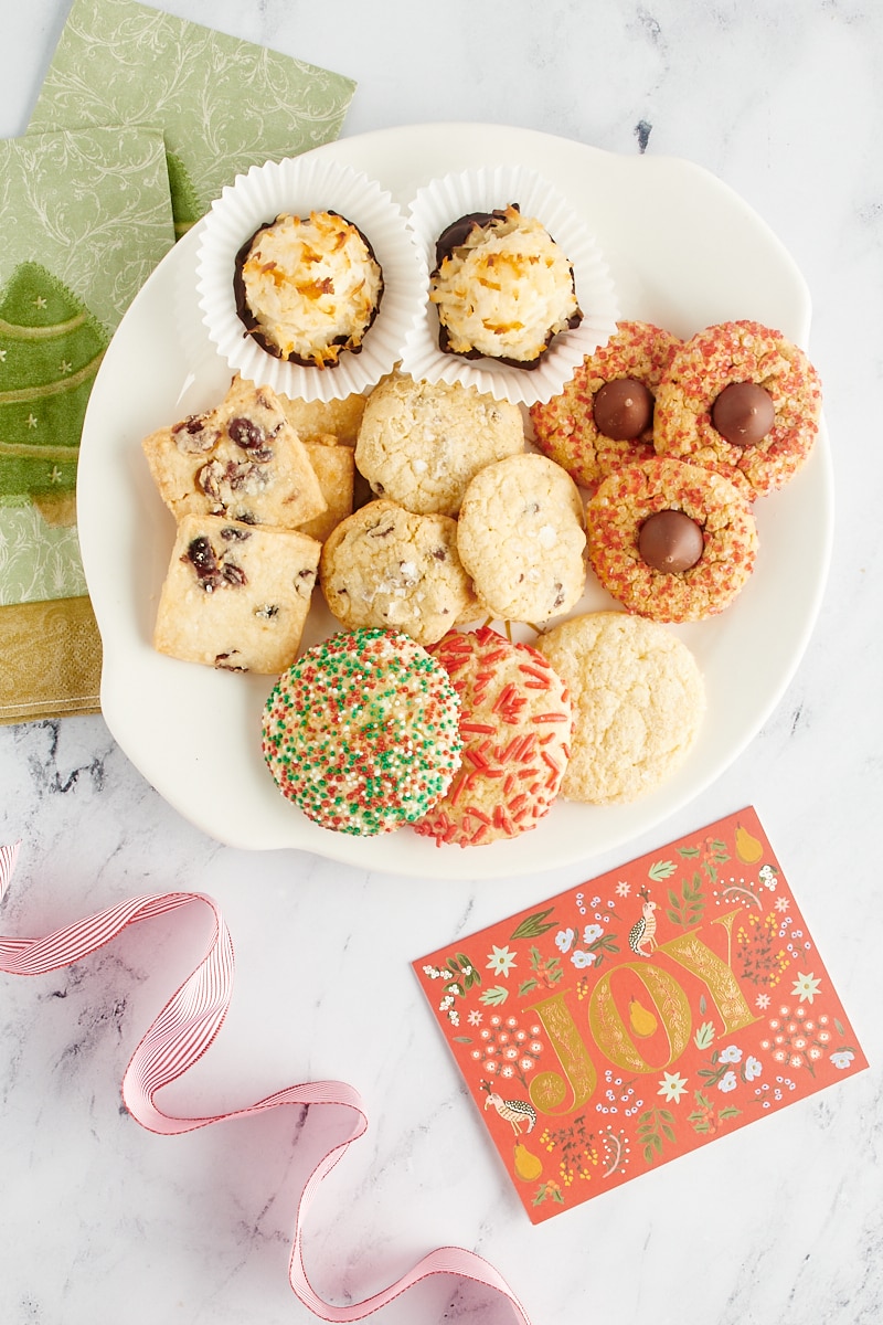 overhead view of Christmas cookies on a round tray with napkins and ribbon alongside