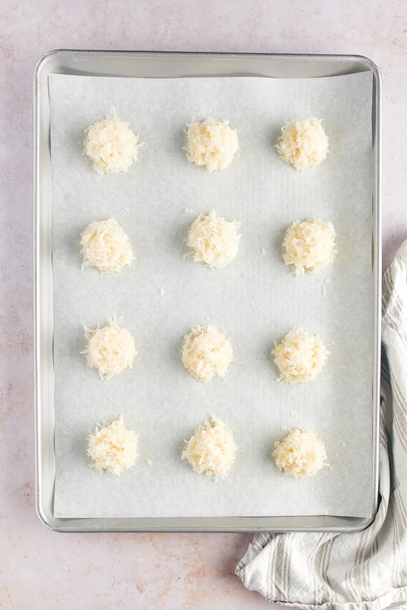 overhead view of portioned Coconut Macaroons on a parchment-lined baking sheet ready to be baked