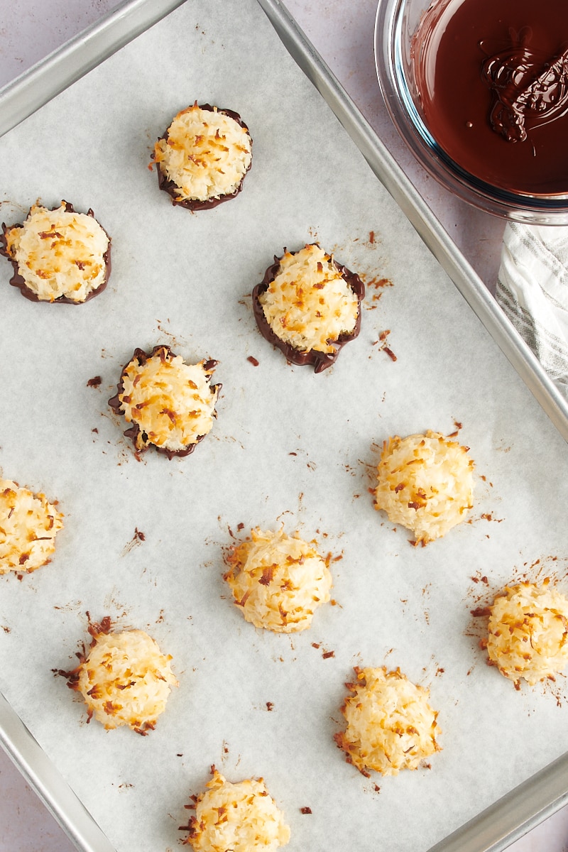 overhead view of Coconut Macaroons on parchment paper, with some dipped in melted dark chocolate