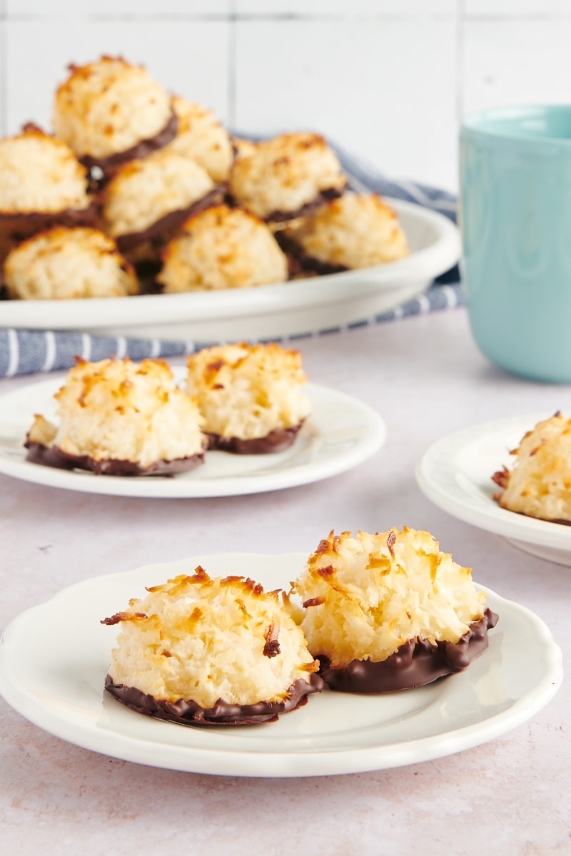 two Coconut Macaroons on a white plate with more macaroons in the background