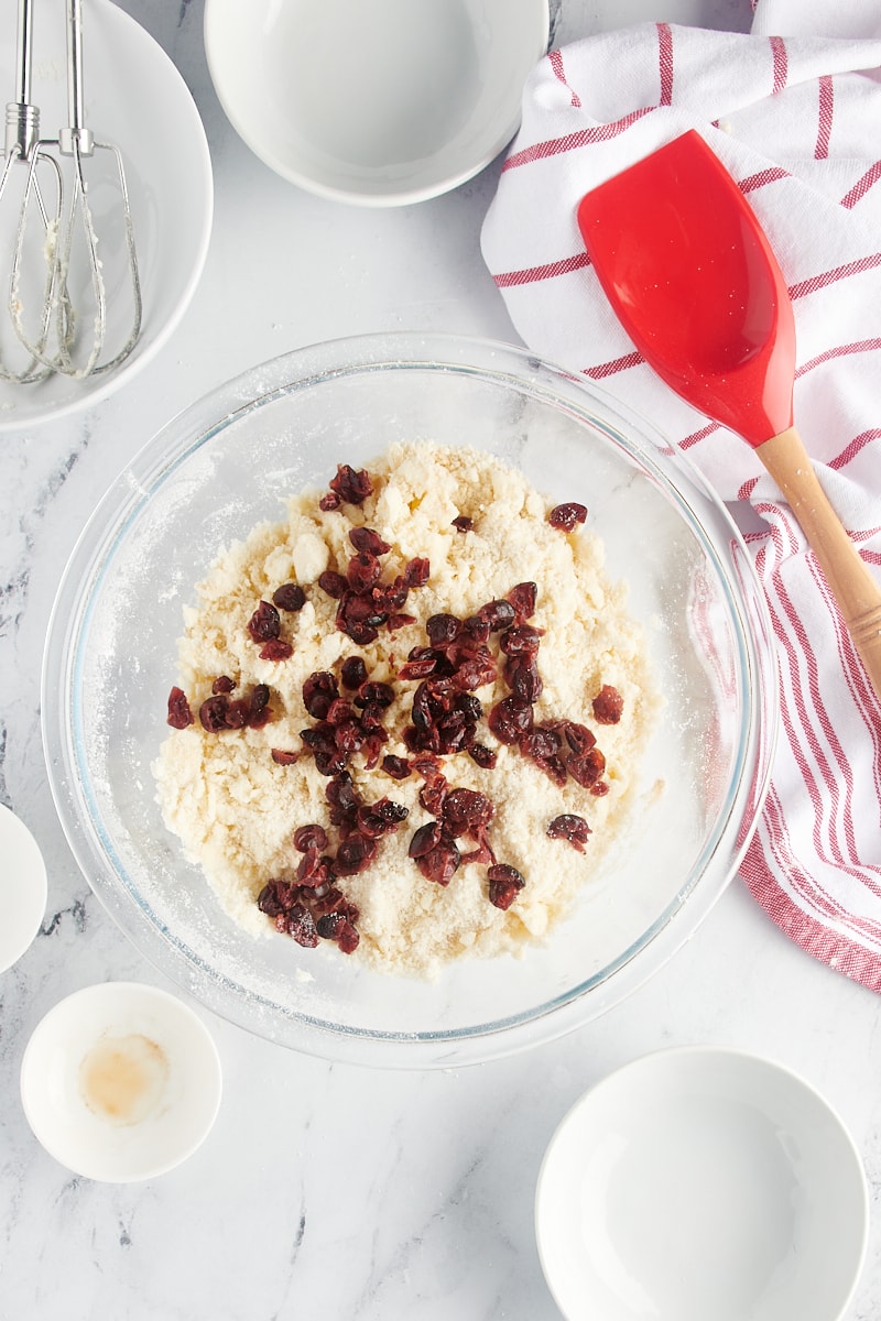 Overhead view of cranberries added to shortbread cookie dough.