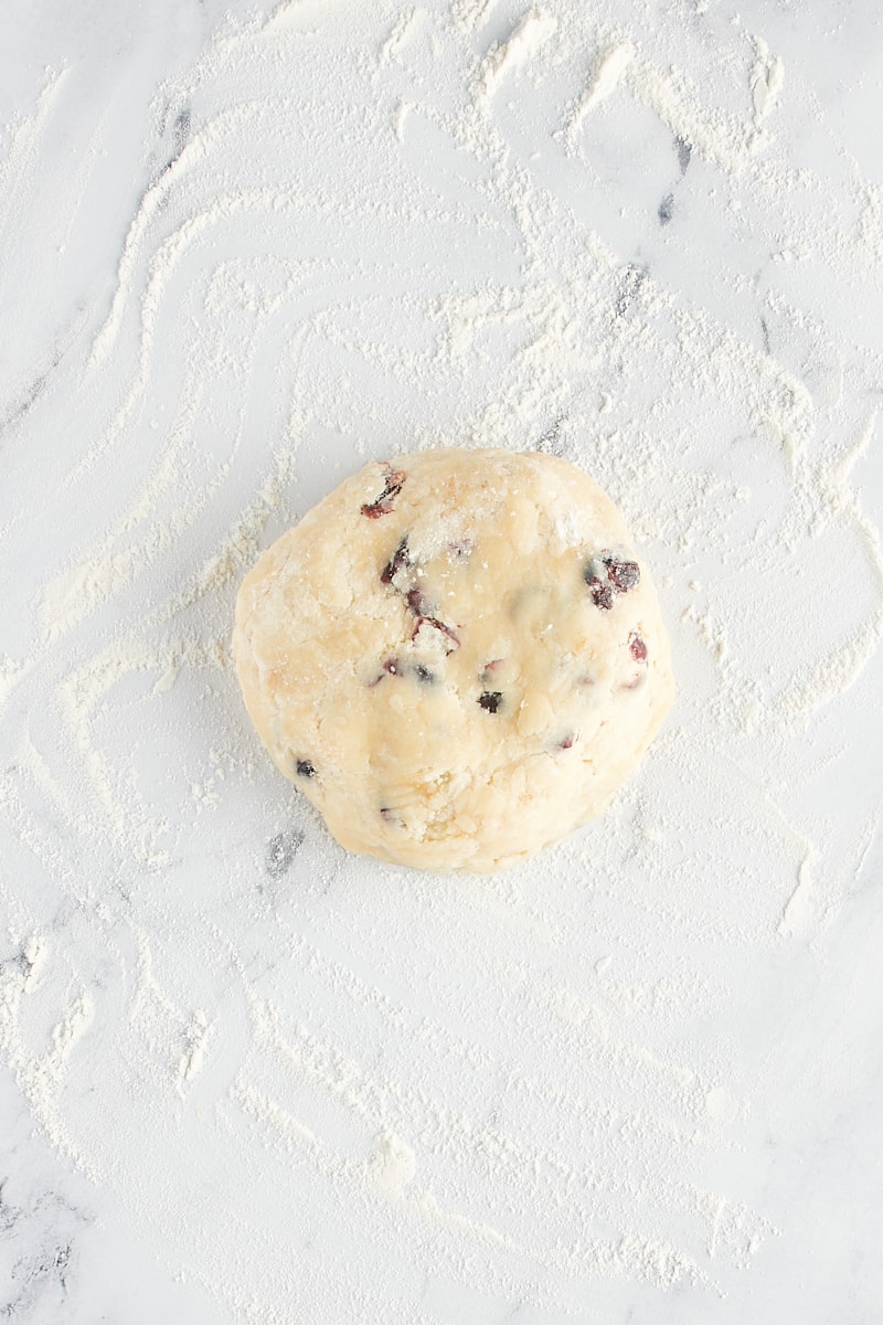 Overhead view of cranberry shortbread cookie dough on a lightly floured surface.