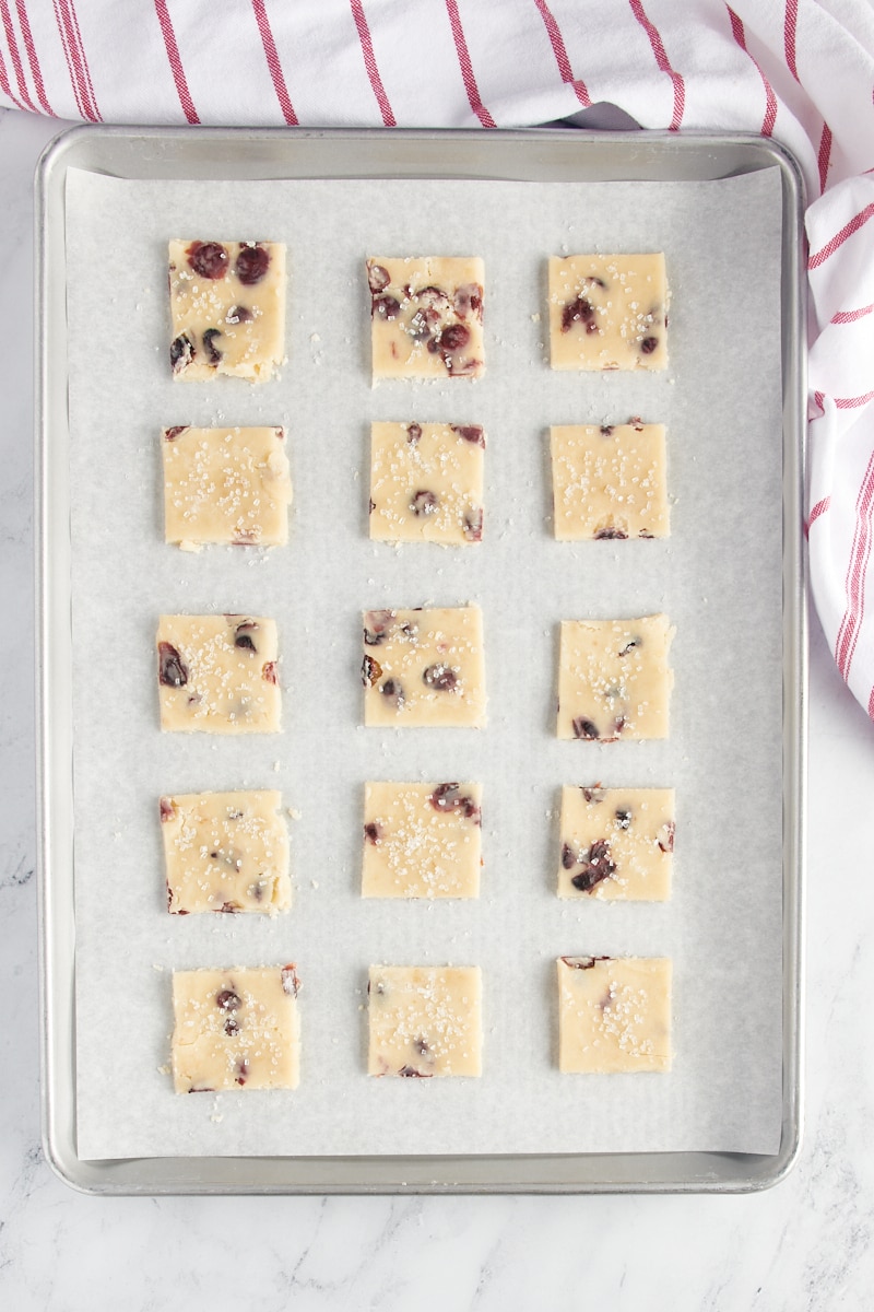 Overhead view of cranberry shortbread cookies on a parchment-lined baking sheet ready to go into the oven.