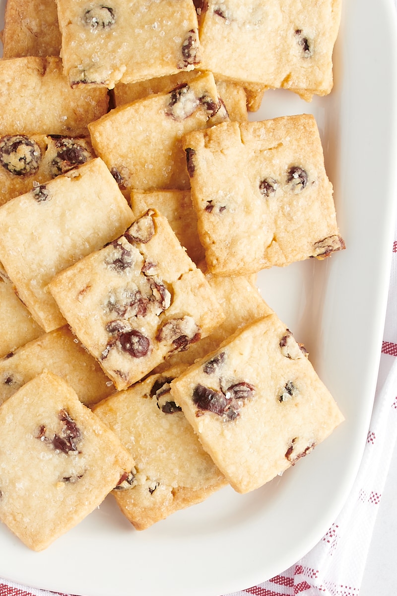 Overhead view of cranberry shortbread cookies piled on a white serving tray.