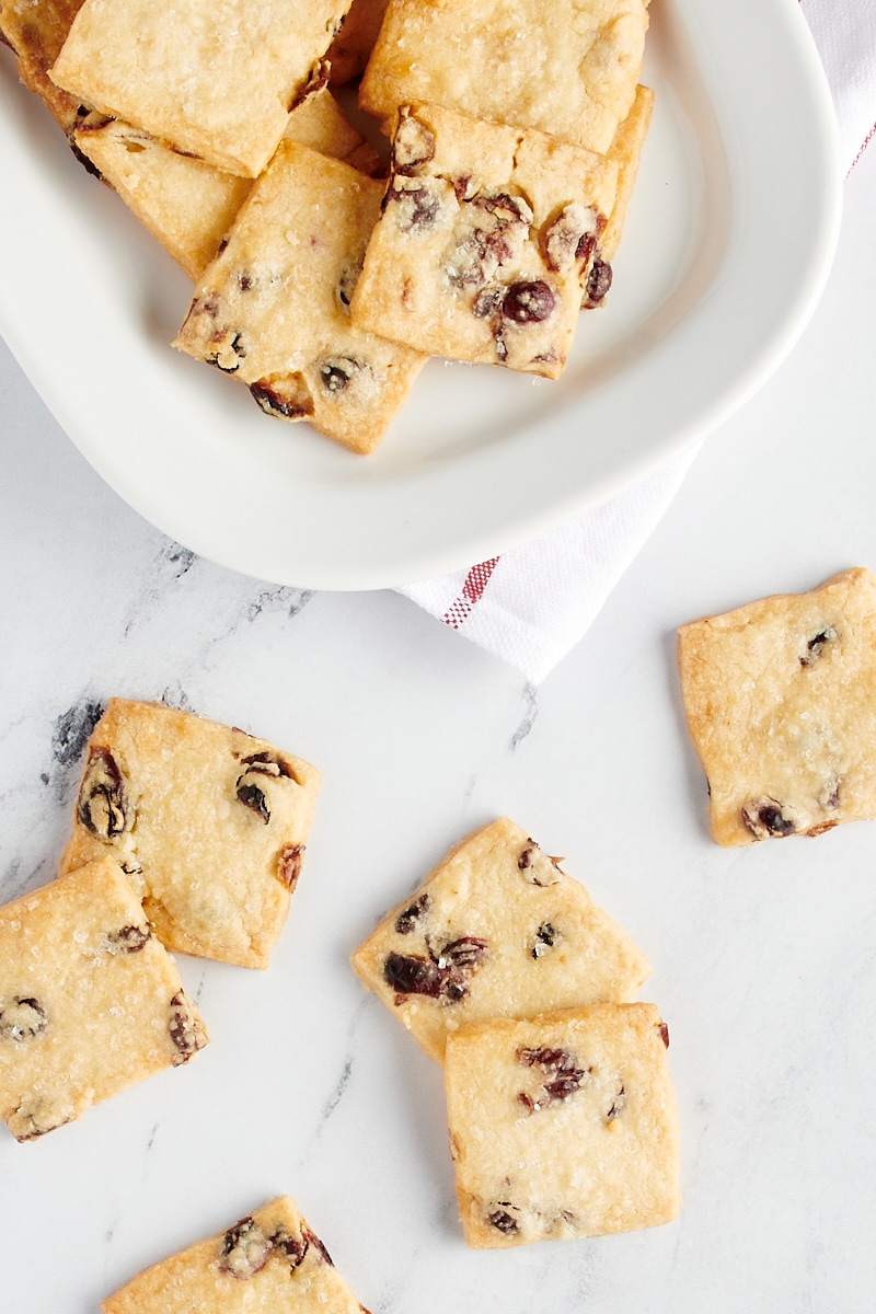 overhead view of Cranberry Shortbread Cookies scattered on a marble countertop and on a large white plate