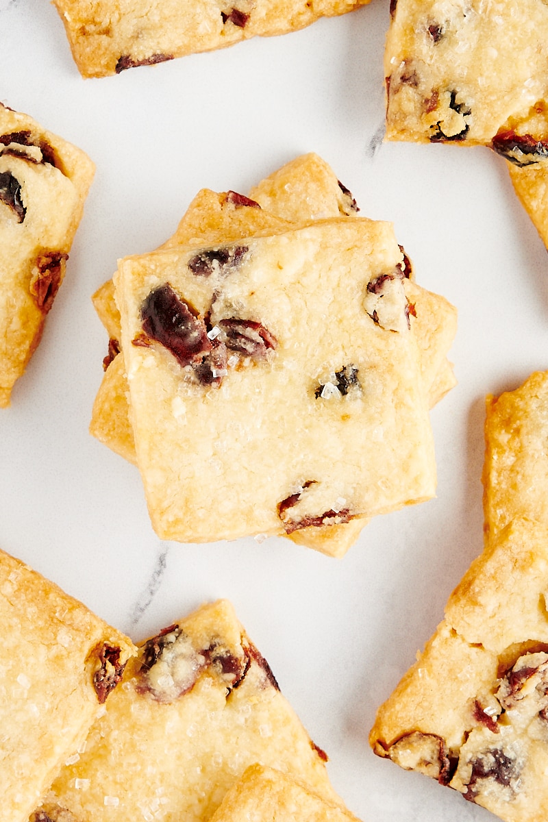 Overhead view of a stack of cranberry shortbread cookies surrounded by more cookies.