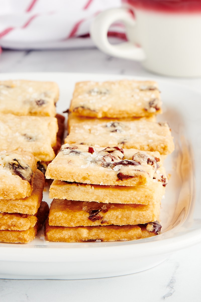 Stacks of cranberry shortbread cookies on a rectangular white plate.