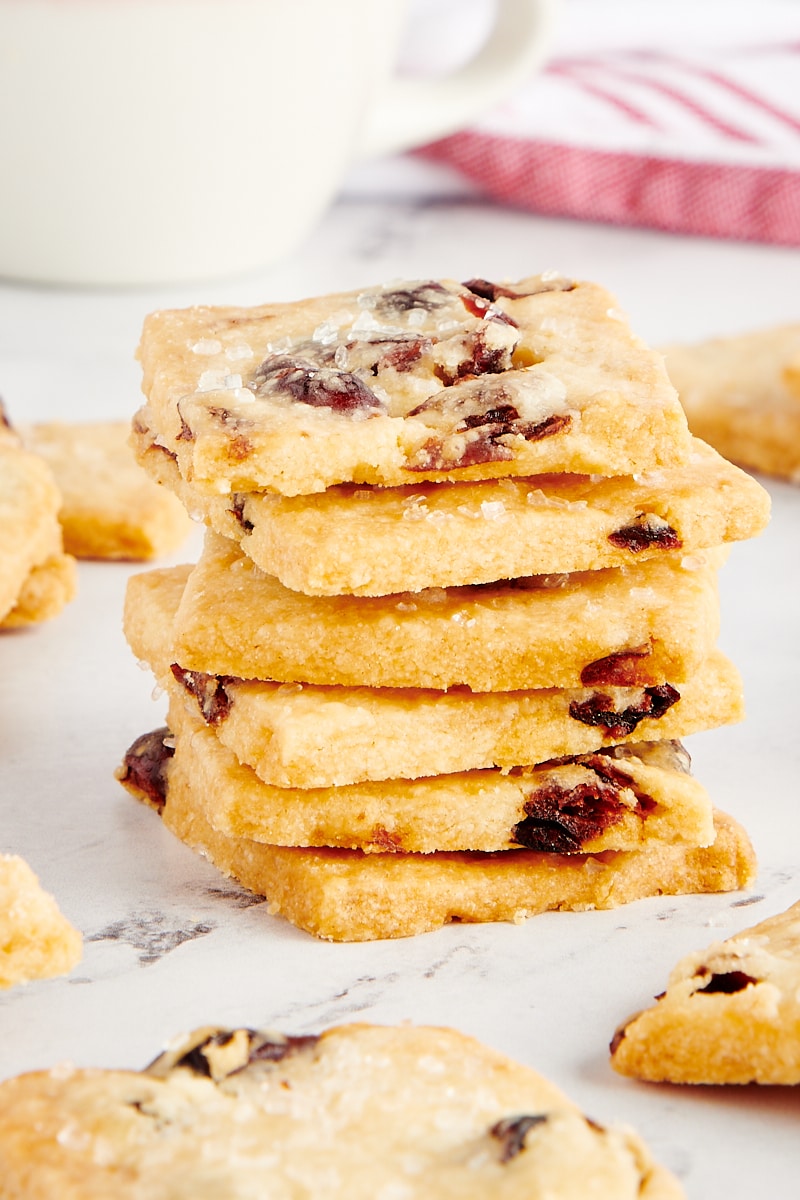 Stack of cranberry shortbread cookies with more cookies surrounding the stack.