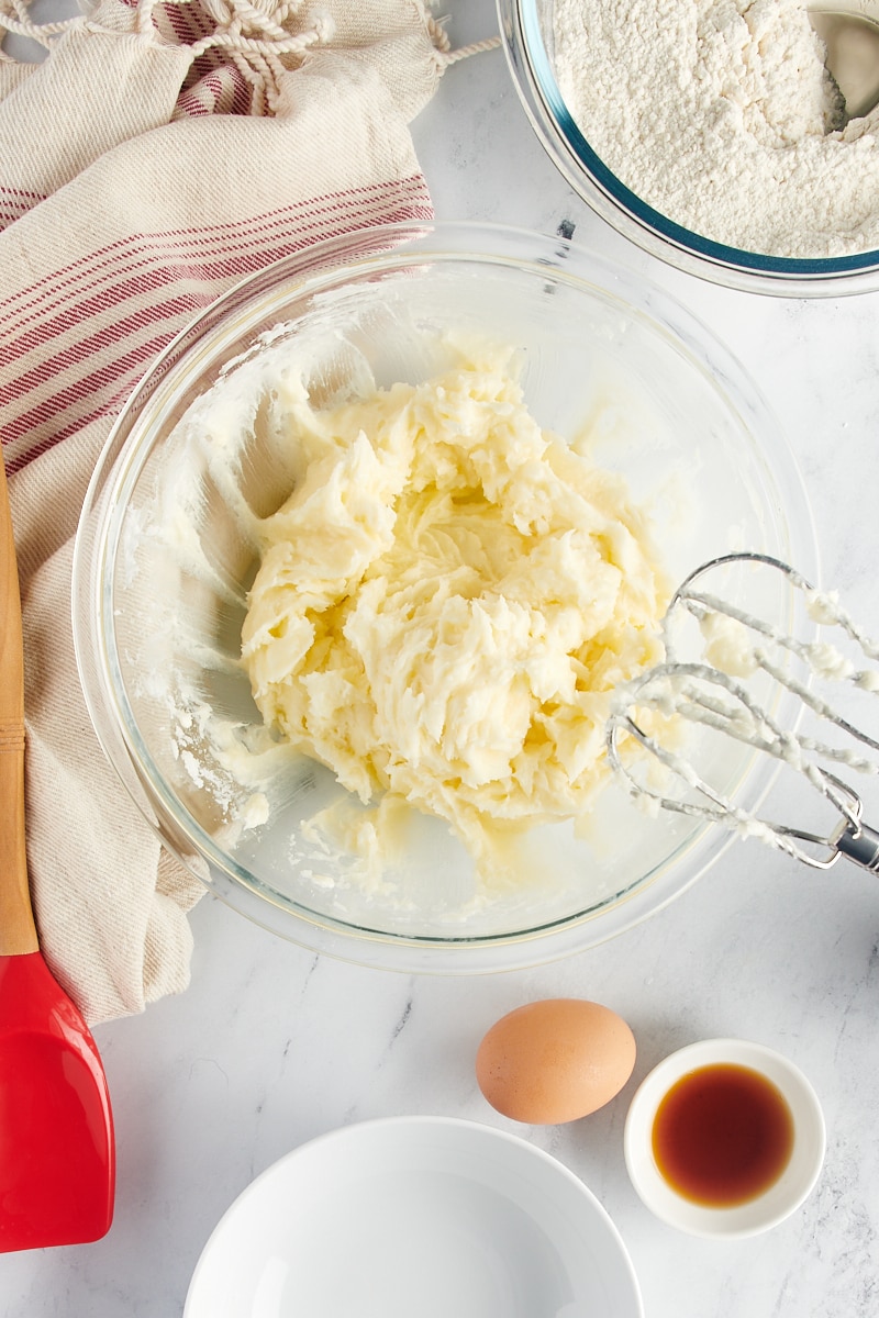 Overhead view of creamed butter, cream cheese, and sugar in a glass mixing bowl.