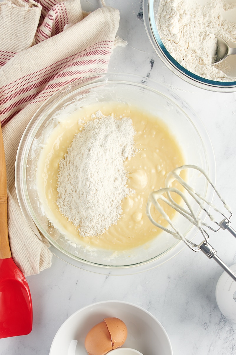 Overhead view of dry ingredients added to wet ingredients for sugar cookies.