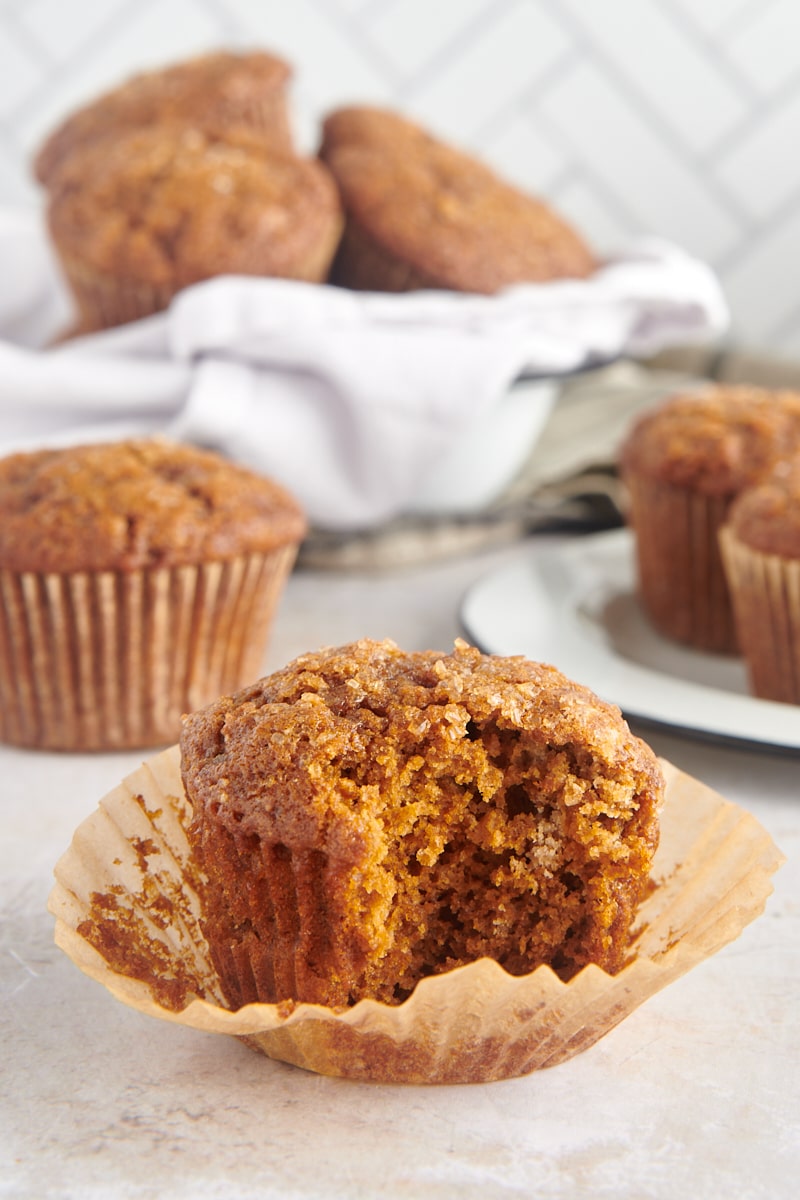 a Gingerbread Muffin with a bite missing, with more muffins in the background