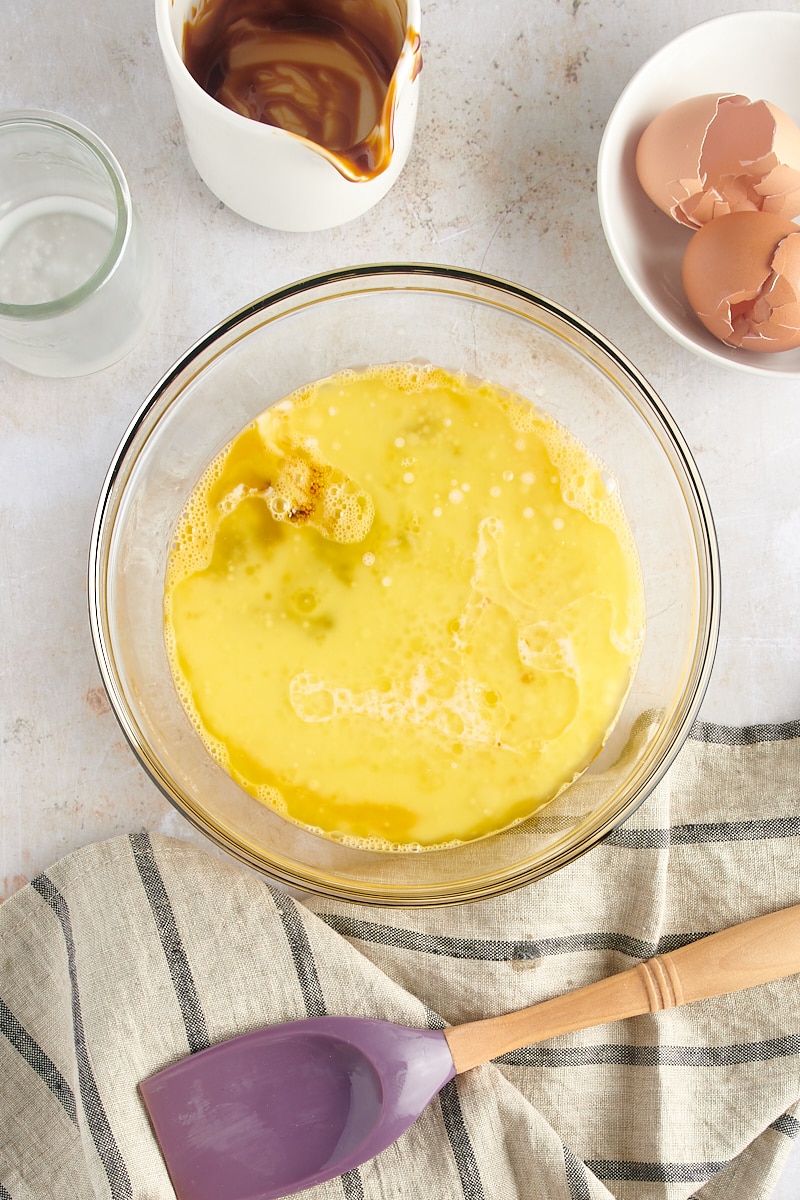 overhead view of eggs, butter, molasses, and milk in a glass mixing bowl