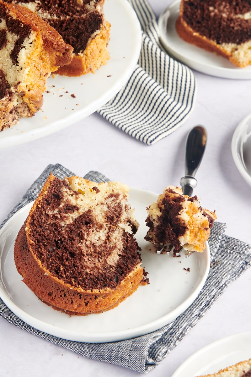 slice of Marble Bundt Cake on a white plate with a bite of cake on a fork