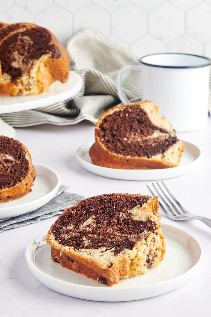 a slice of Marble Bundt Cake on a white plate with more servings in the background