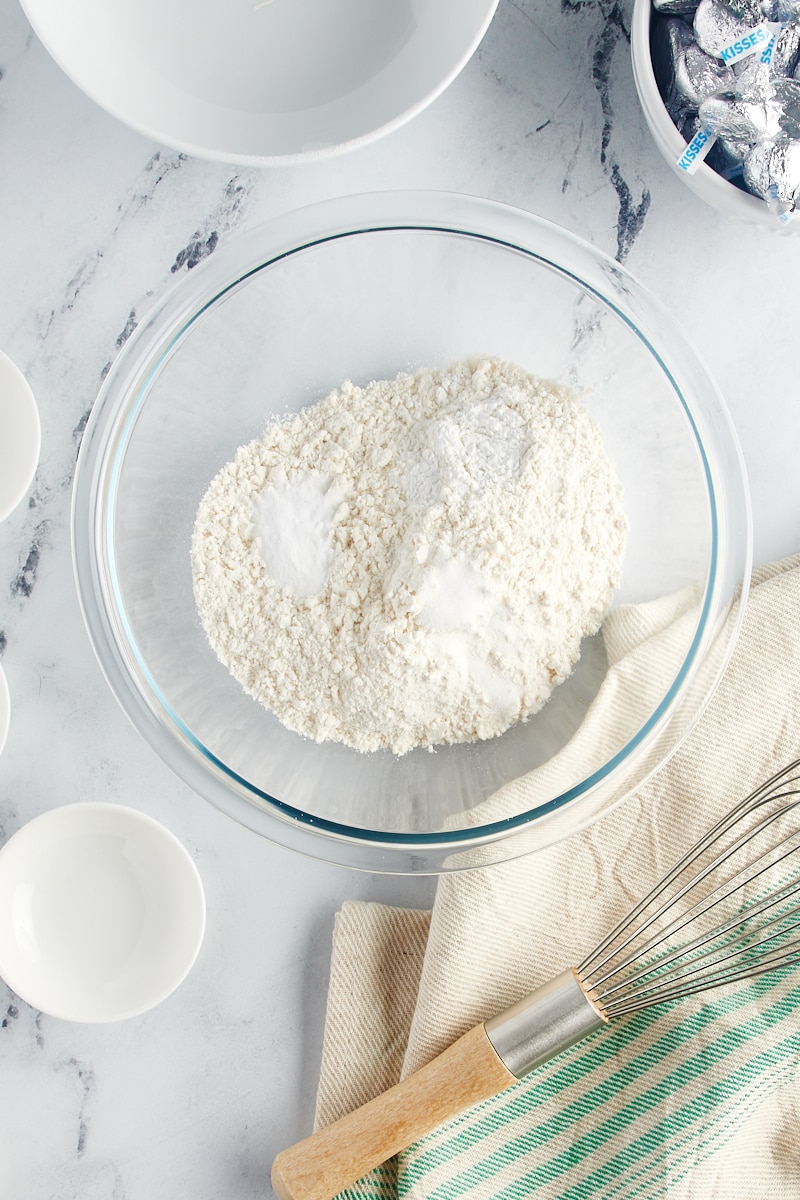 overhead view of flour, bkaing powder, baking soda, and salt in a glass mixing bowl