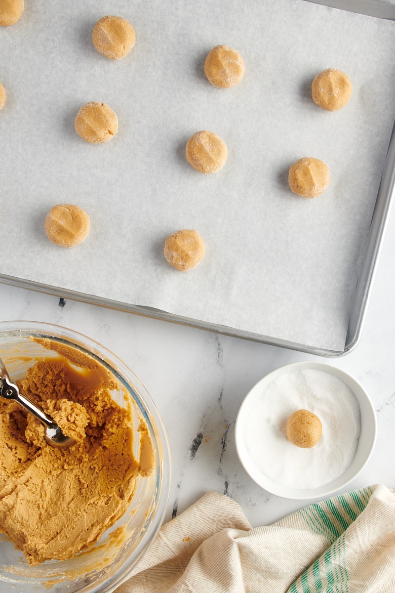 overhead view of sugar-coated peanut butter cookie dough on a baking sheet 