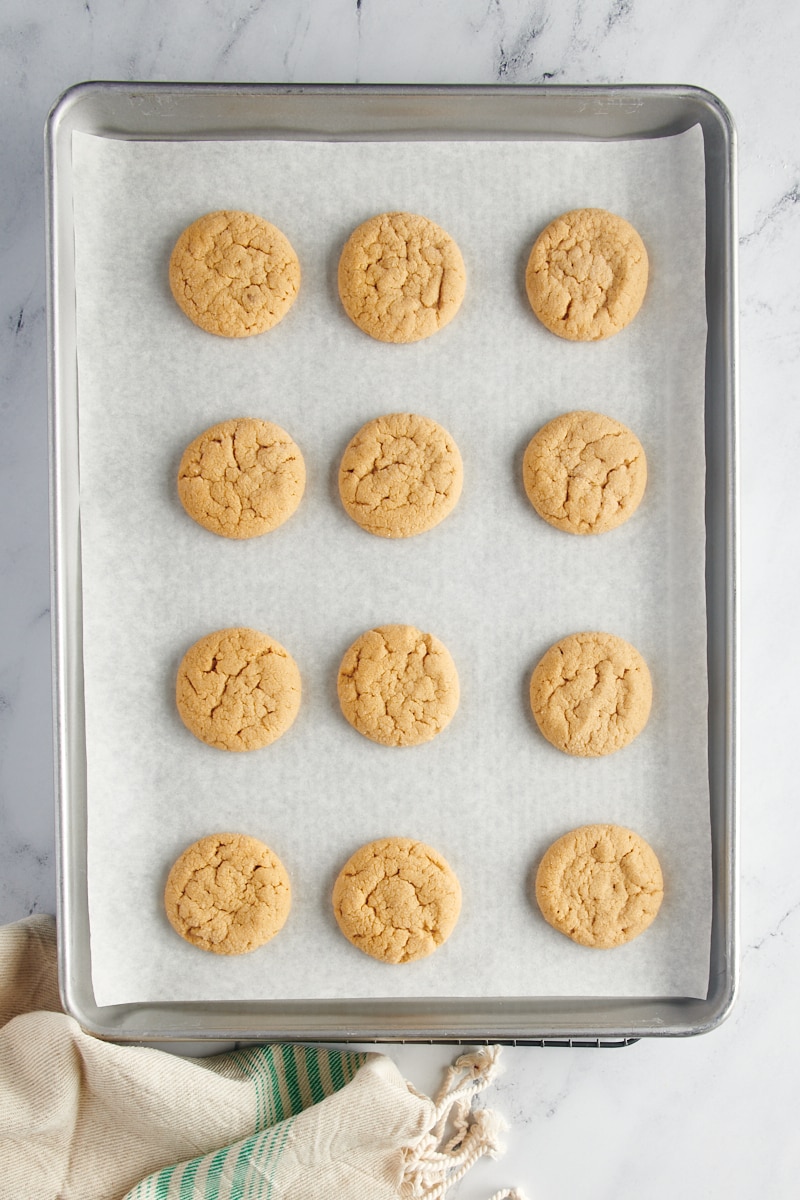overhead view of freshly baked peanut butter cookies on a parchment-lined baking sheet