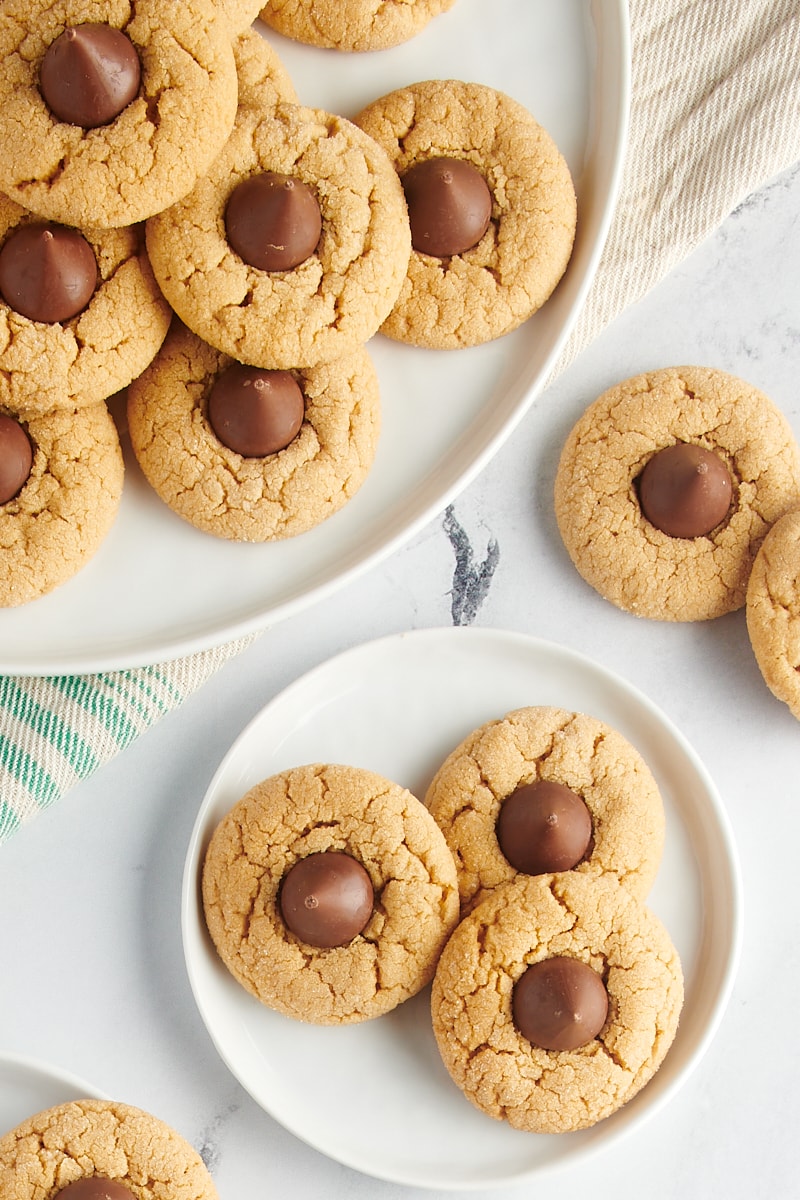 overhead view of Peanut Butter Blossoms on a small white plate and a large white tray