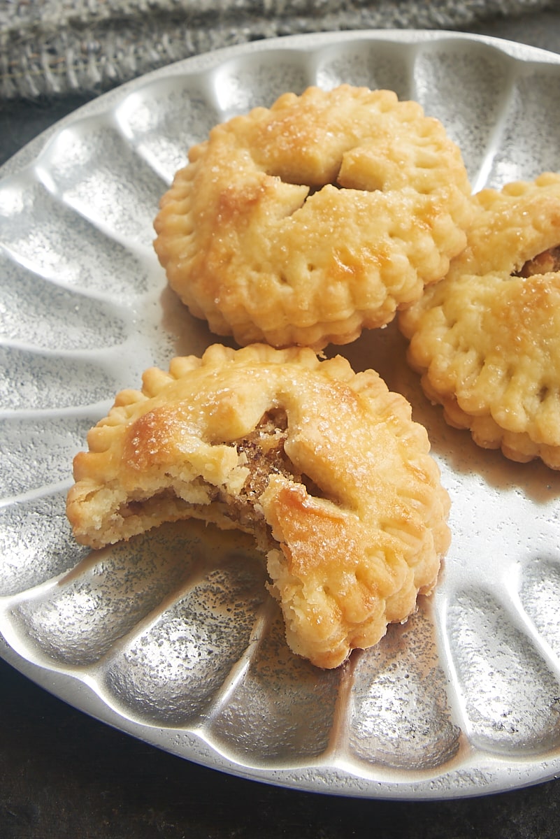 a Pecan Hand Pie with a bite missing, on a plate with two more pies