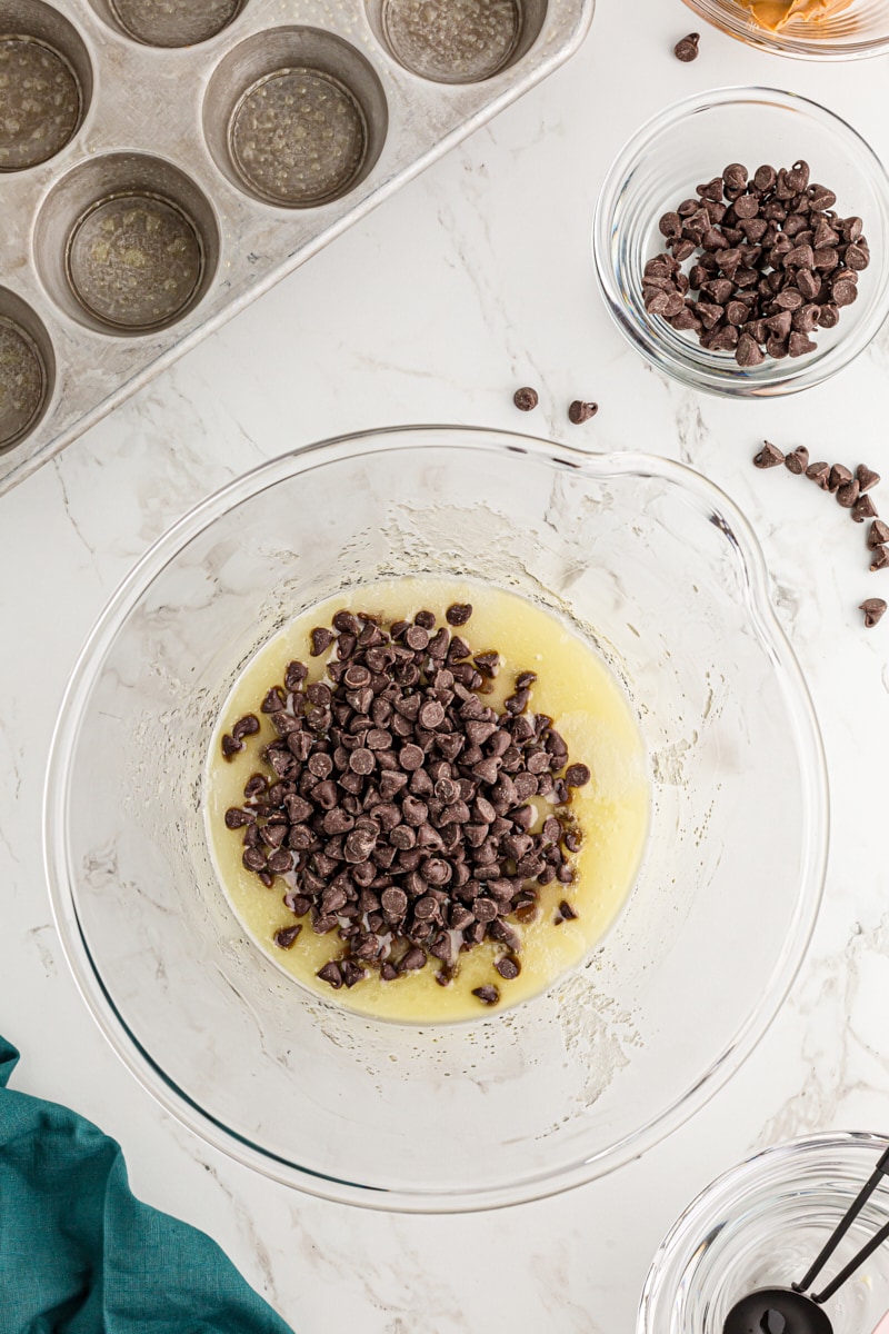 Overhead view of chocolate chips in bowl with melted butter and sugar