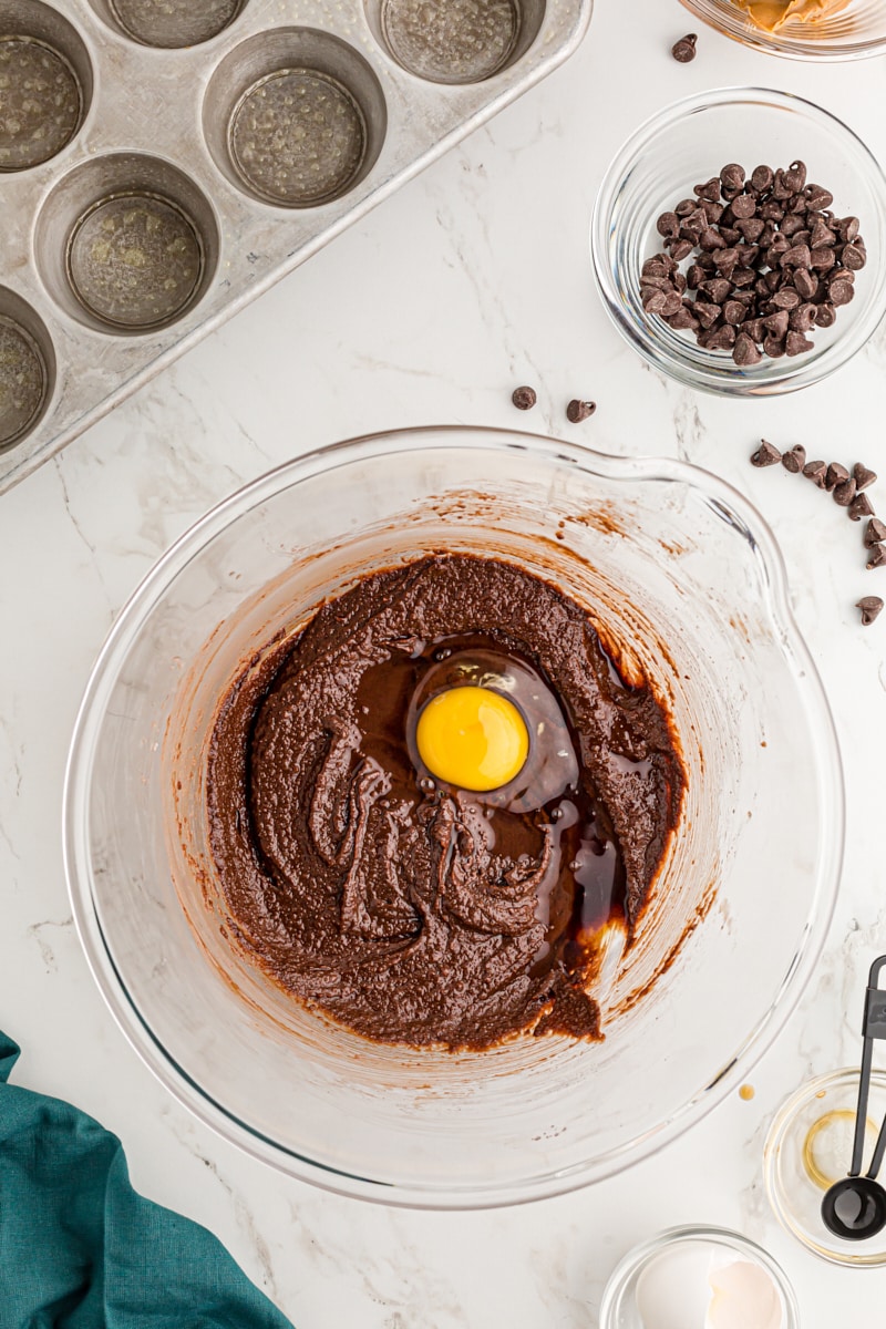 Overhead view of egg added to bowl of brownie batter