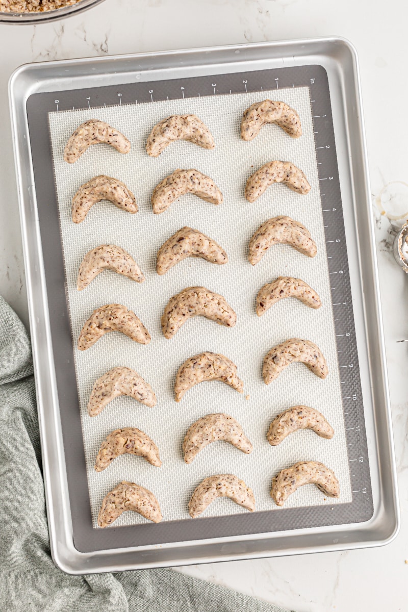 Overhead view of unbaked hazelnut crescent cookies on pan