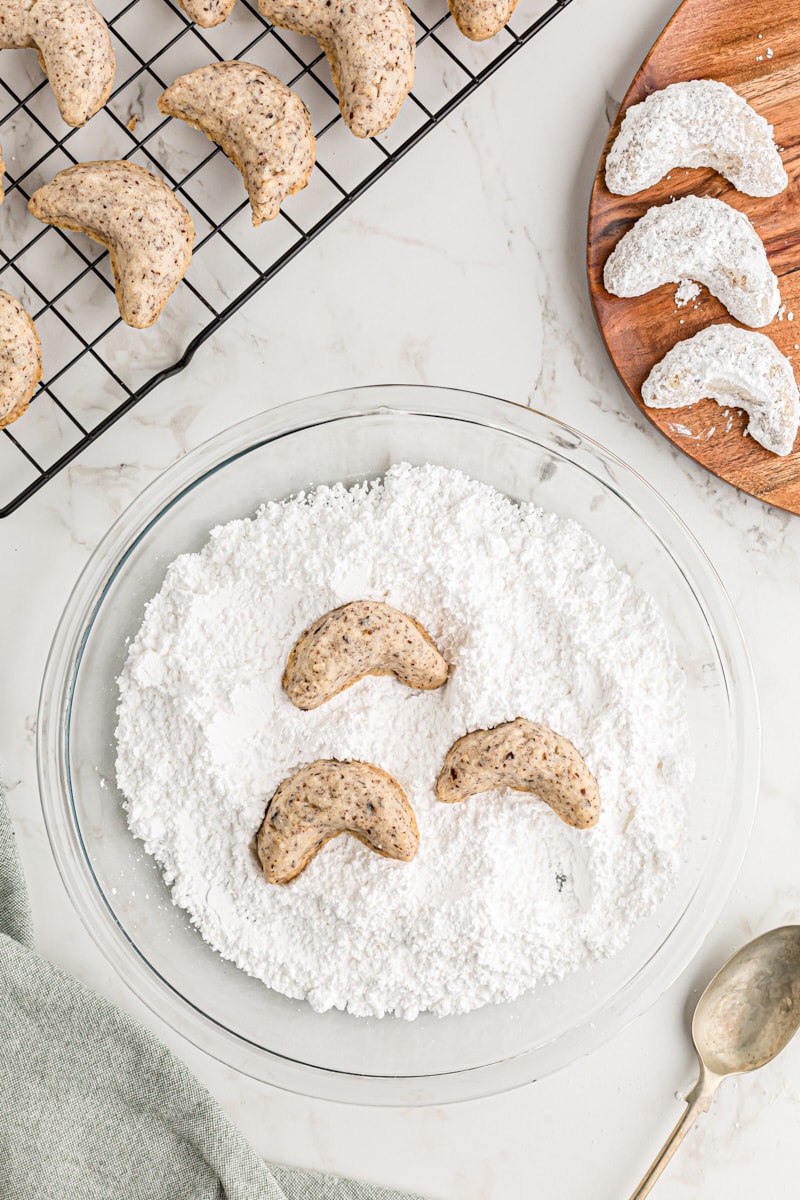 Overhead view of nut crescent cookies in bowl of powdered sugar