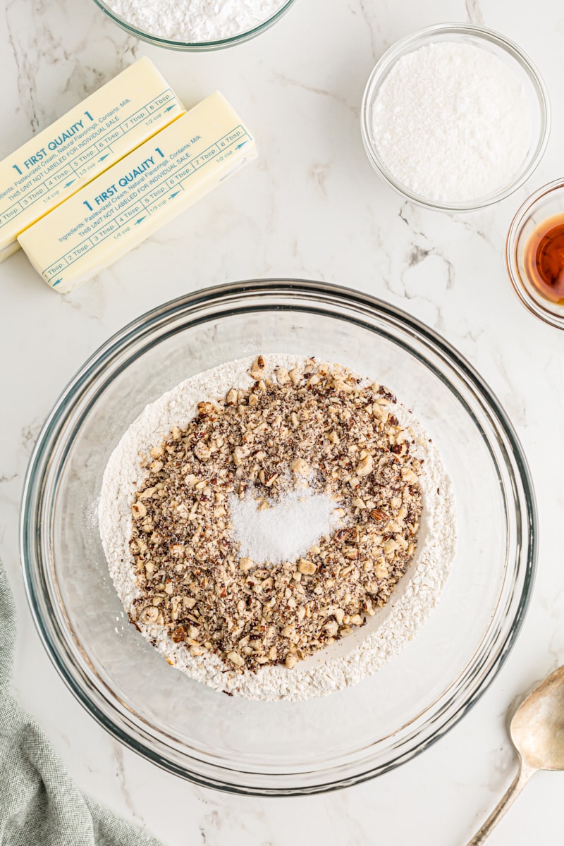 Overhead view of chopped hazelnuts and dry cookie ingredients in bowl