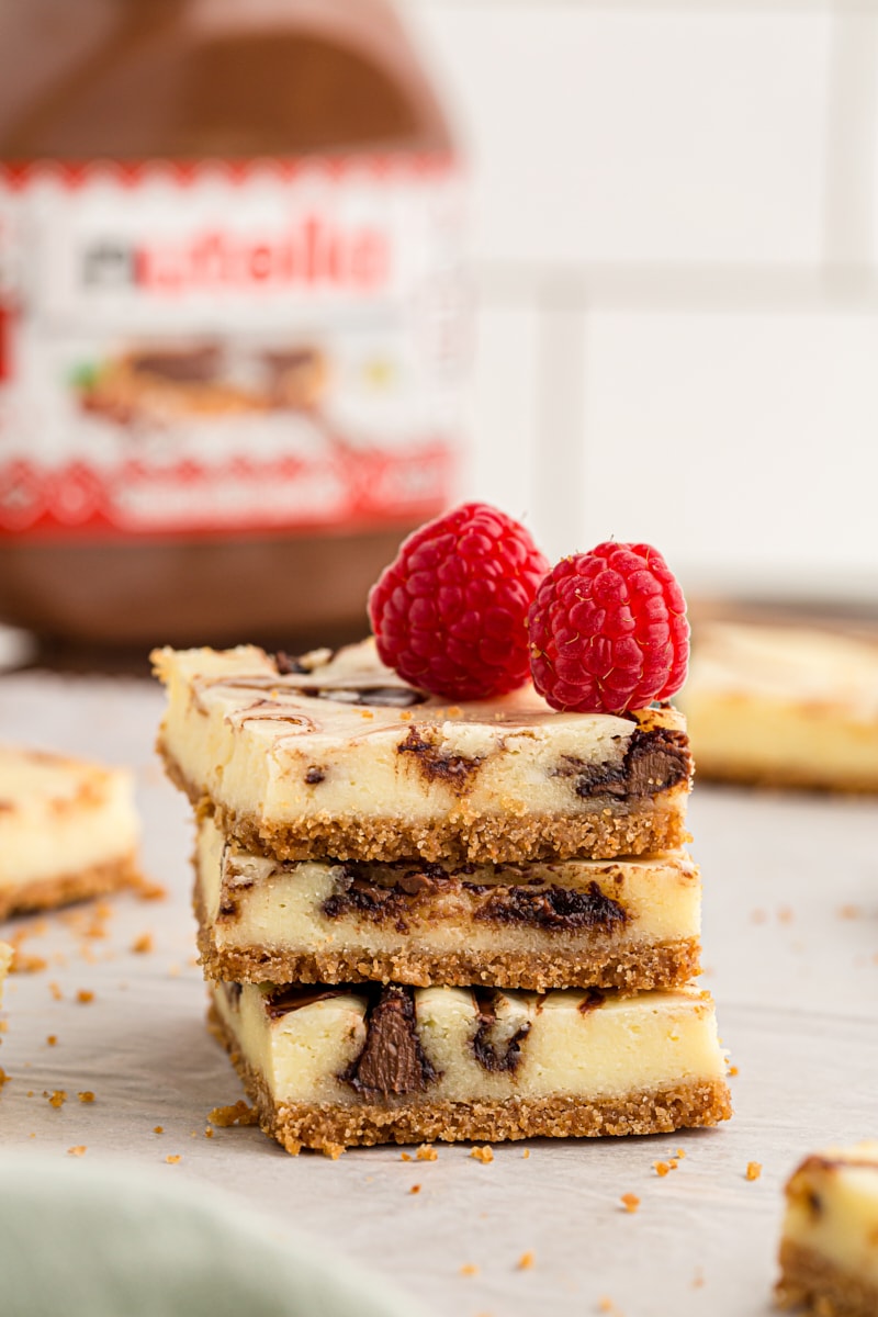 Stack of 3 Nutella swirl cheesecake bars with 2 raspberries on top