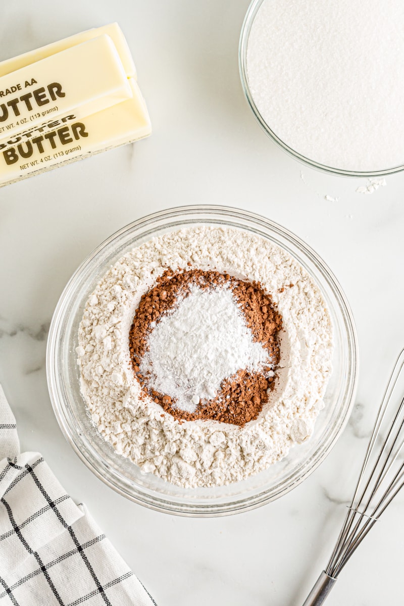 overhead view of flour, cocoa powder, baking powder, baking soda, and salt in a glass mixing bowl