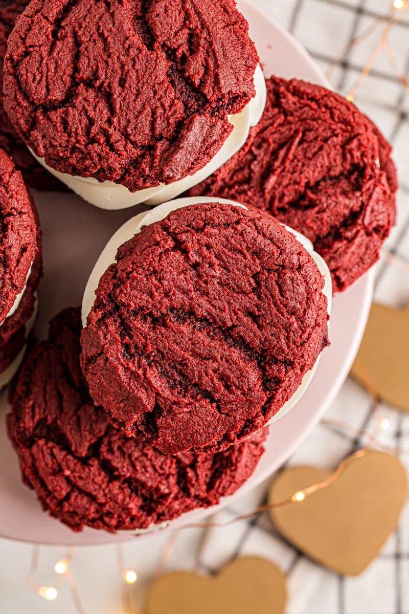 overhead view of Red Velvet Cookies on a pale pink cake stand with paper hearts and tiny lights underneath