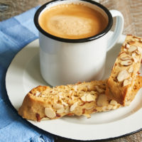 two Almond Biscotti on a white plate with a mug of coffee