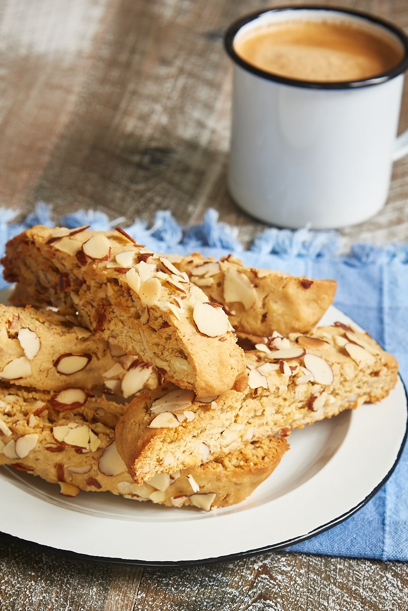 Almond Biscotti served on a white plate with a mug of coffee in the background