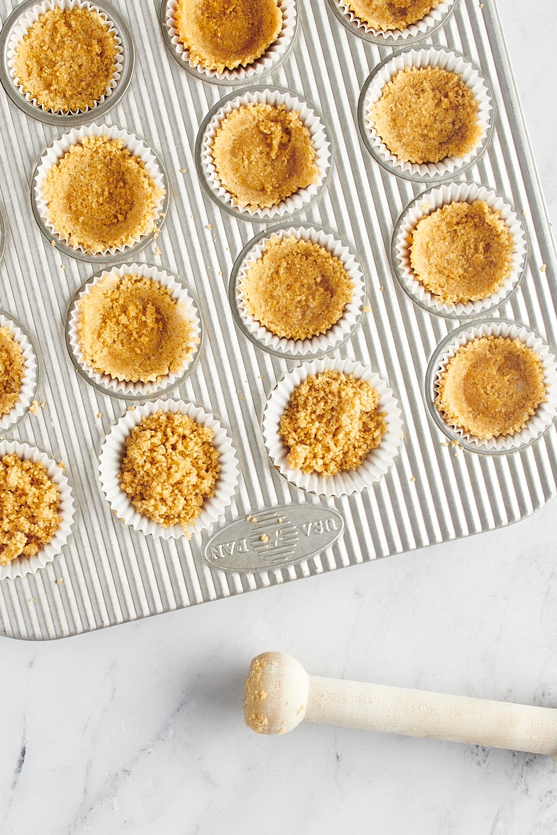 Graham cracker crust mixture in a mini muffin tin.