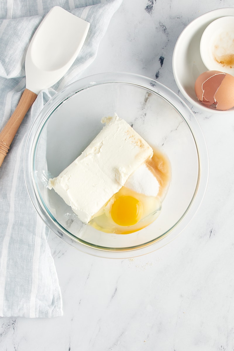 Cheesecake filling ingredients in a glass mixing bowl.