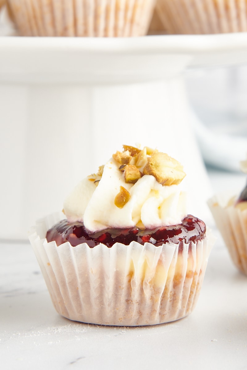 Mini cheesecake topped with jam, whipped cream, and nuts.