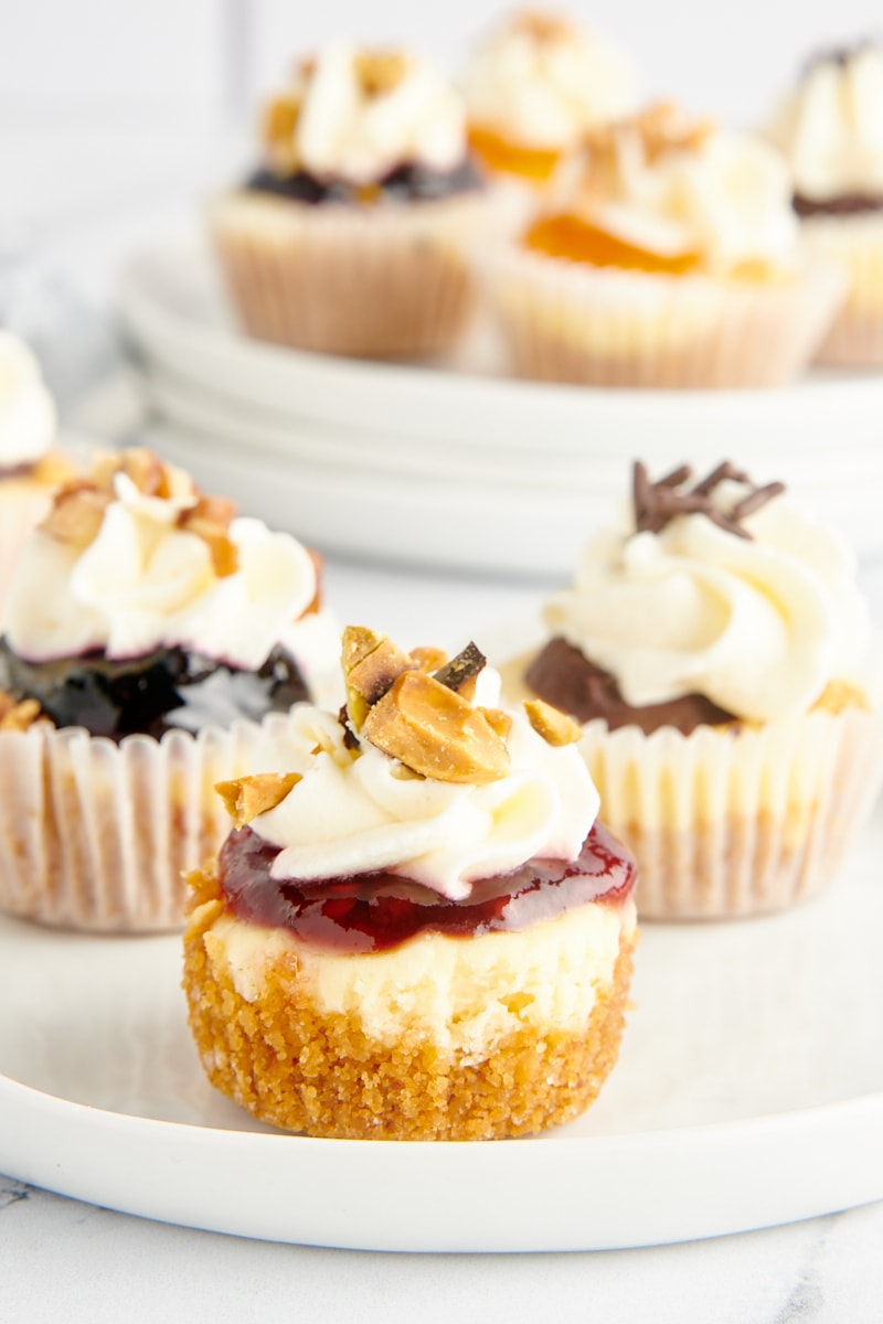 3 mini cheesecakes on a plate with different toppings.