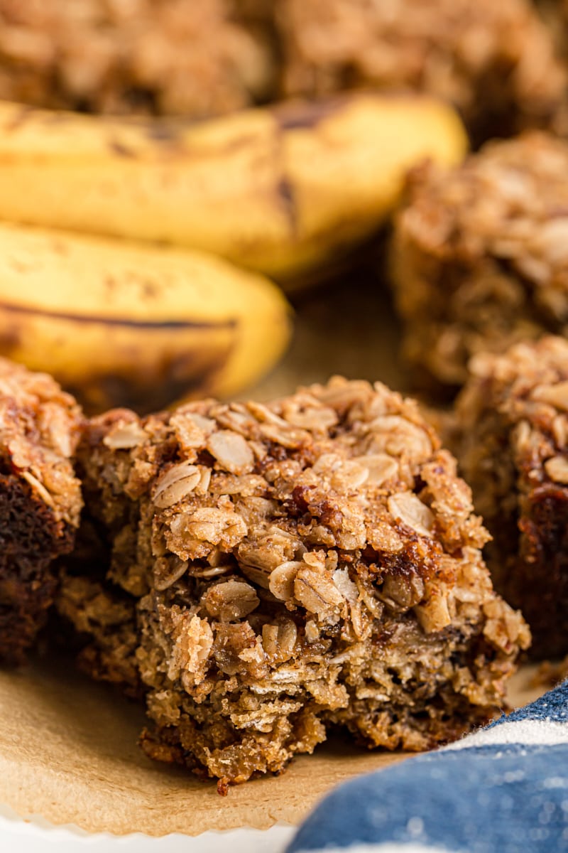 Pieces of banana oatmeal crumb cake with bananas in background