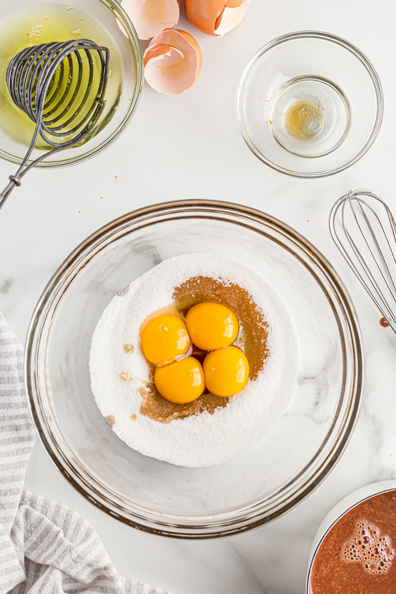 Overhead view of egg yolks, sugar, and vanilla in mixing bowl