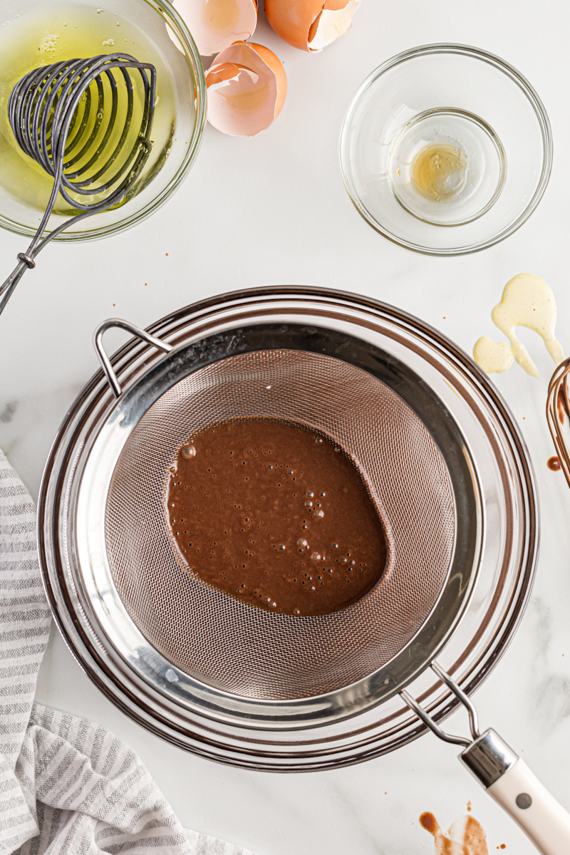 Overhead view of chocolate custard being poured through sieve