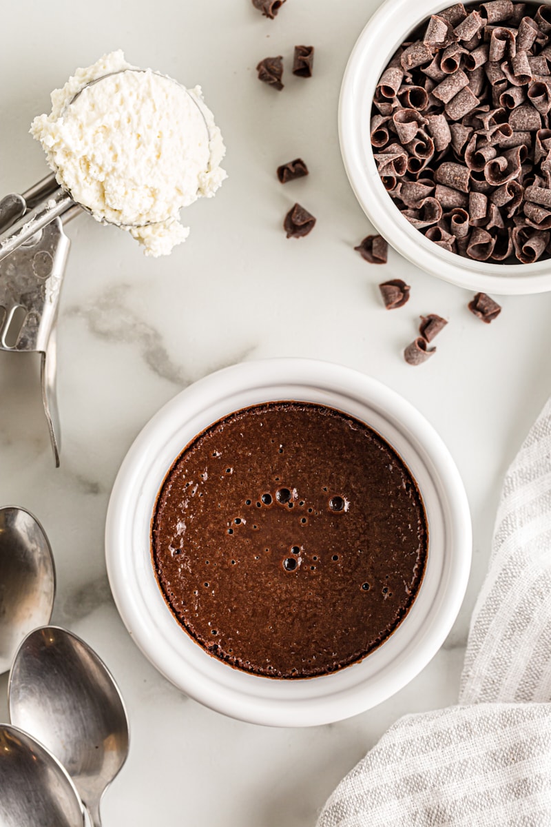 Overhead view of chocolate pots de creme, scoop of ice cream, and bowl of chocolate shavings