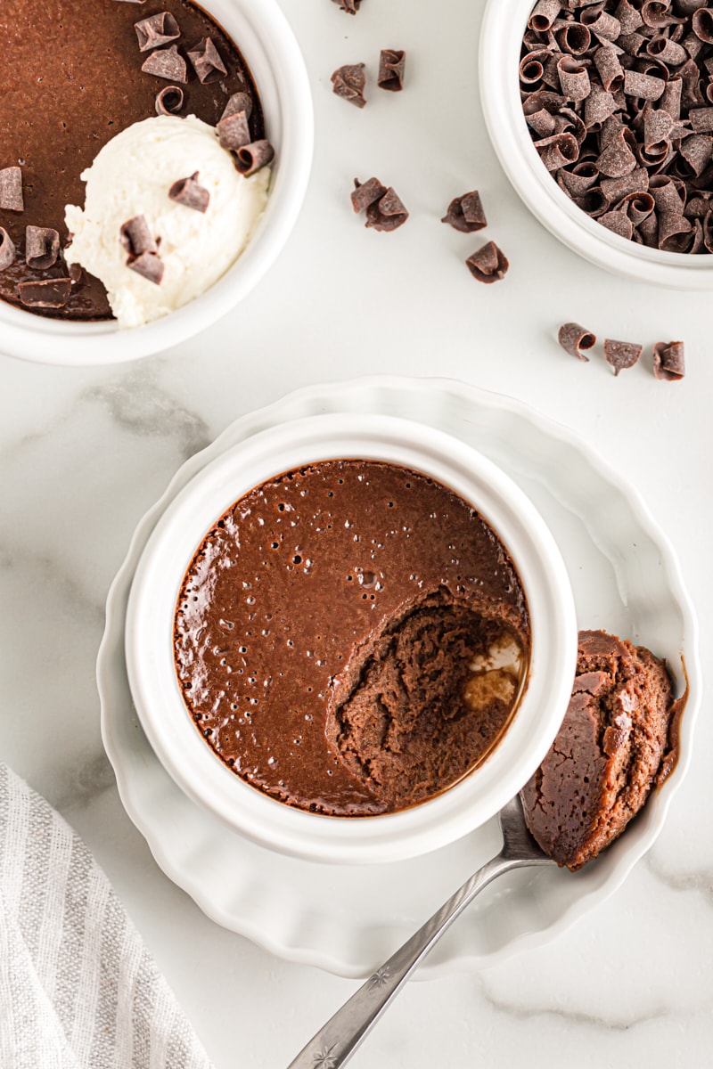 Overhead view of chocolate pot de creme on white plate with spoonful of creme removed