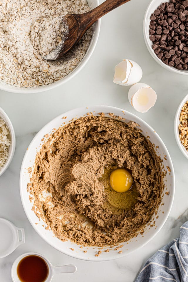 Overhead view of egg cracked into mixing bowl with cookie dough