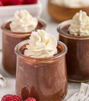 3 jars of double chocolate pudding with whipped cream on top