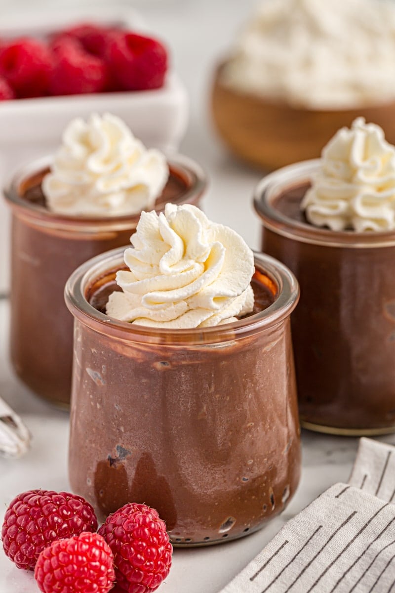 3 jars of double chocolate pudding with whipped cream on top