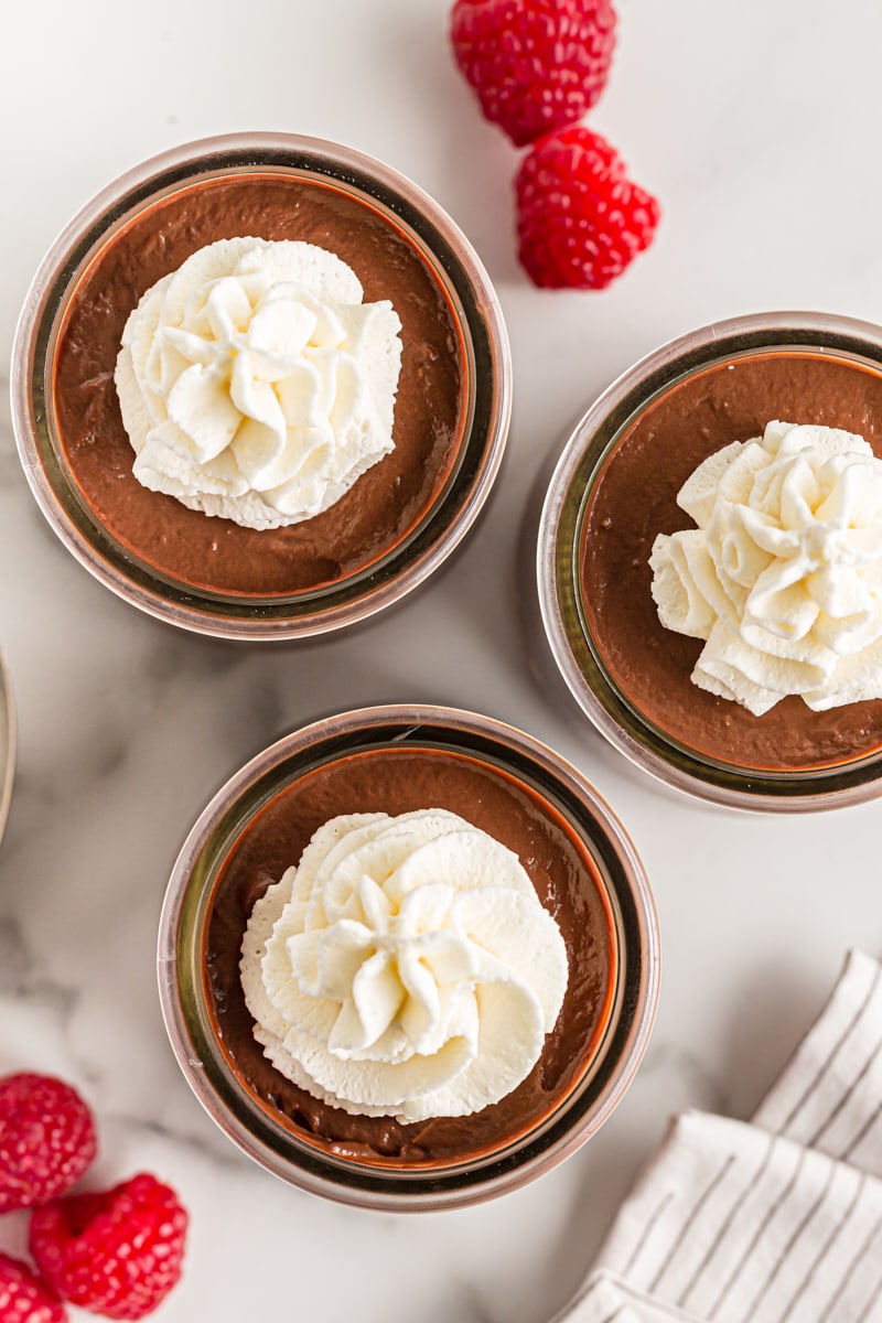 Overhead view of 3 jars of chocolate pudding with whipped cream