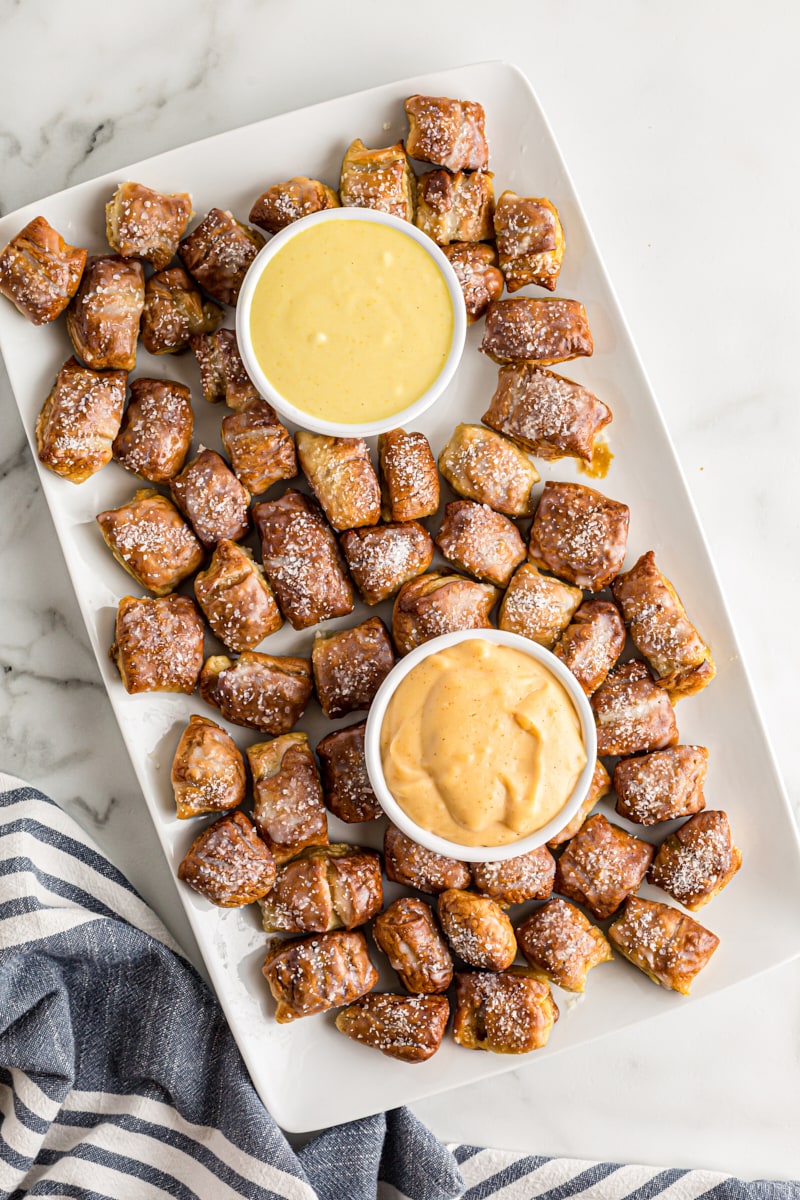 overhead view of Pretzel Bites served on a white platter with honey mustard dipping sauce and beer cheese dip
